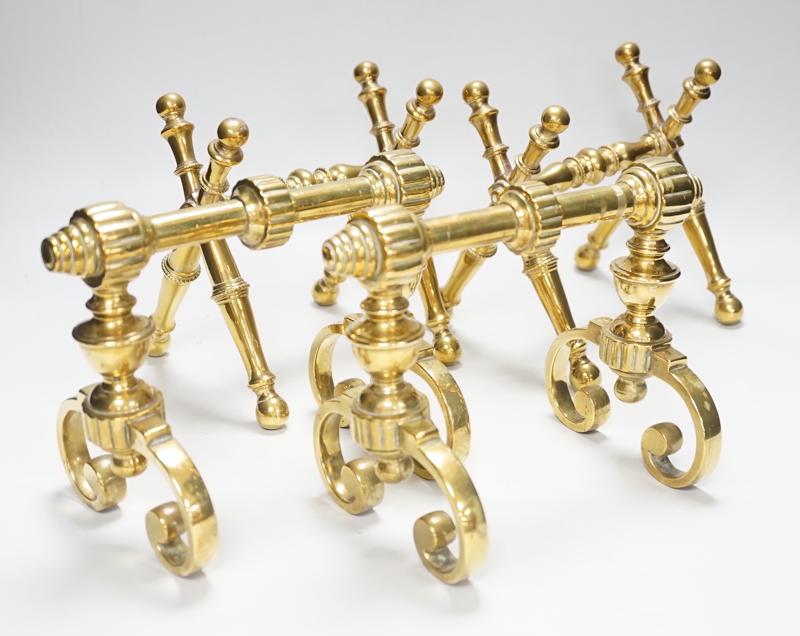 Two sets of brass fire dogs in Christopher Dresser style, the largest 18cm high